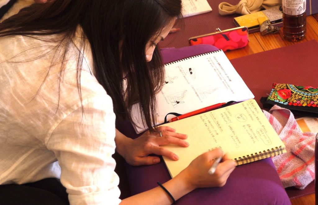 マタニティヨガ指導者養成講座のテキストに書き込みをする女性