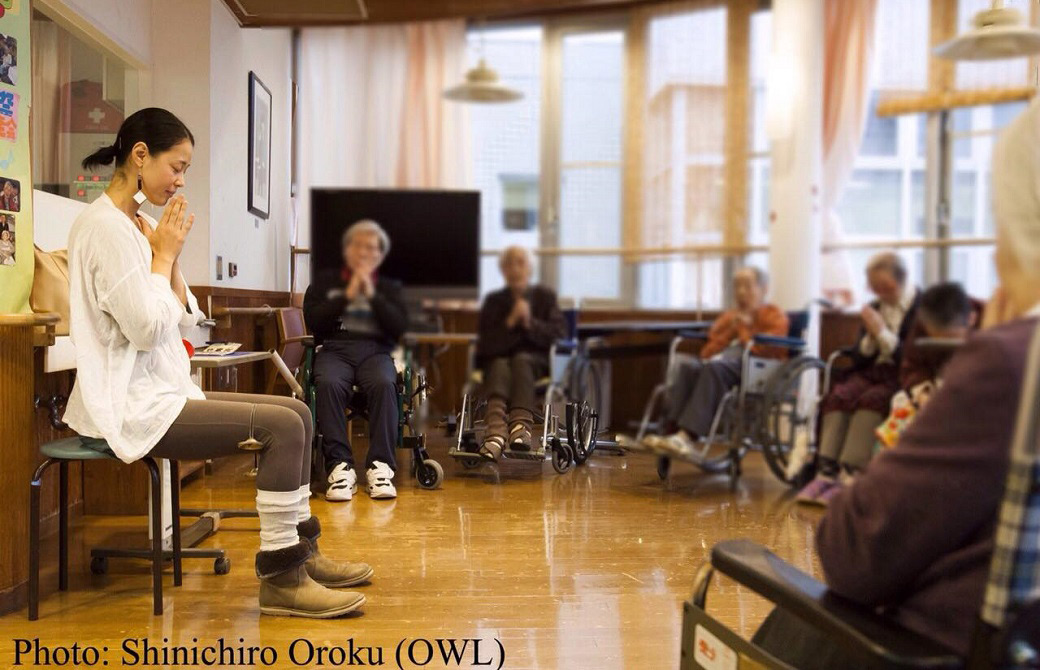 介護施設でヨガをする山田いずみ先生と複数のシニアの生徒さん